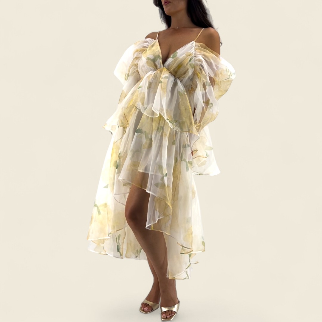 Robe jaune aux tons doux, asymétrique avec une coupe courte devant et longue derrière. Tissu fluide légèrement transparent, doublé sur le corps. Manches tombantes sur les bras et fines bretelles ajustables.